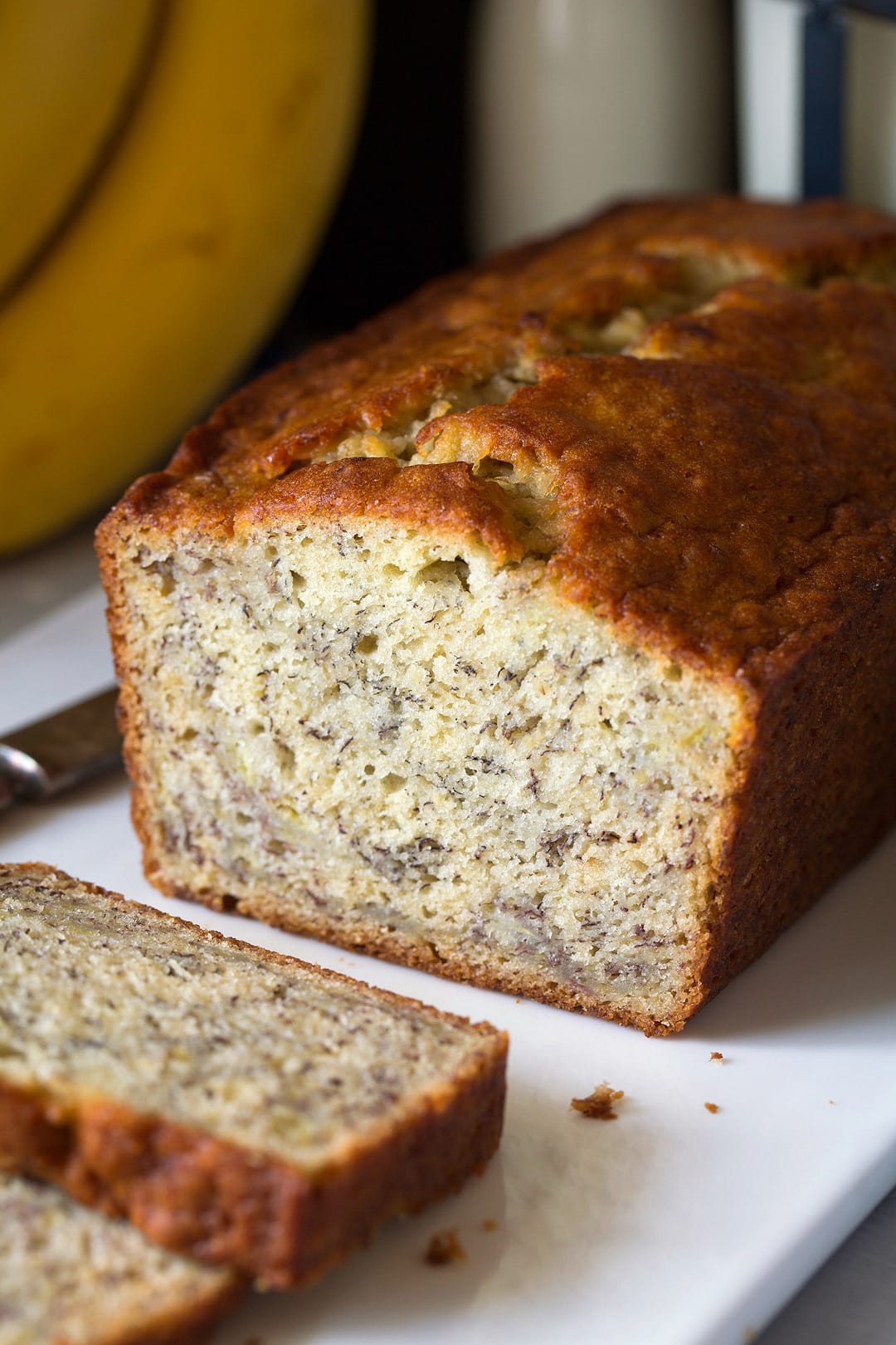 This is the best banana bread recipe! Quick and easy to make and no mixer is required. It's perfectly moist and amazingly tender and it's brimming with banana flavor. Simply put, everyone will have a hard time stopping at just one slice! #cookingclassy #banana #bread #bananabread A loaf of homemade banana bread on a white plate