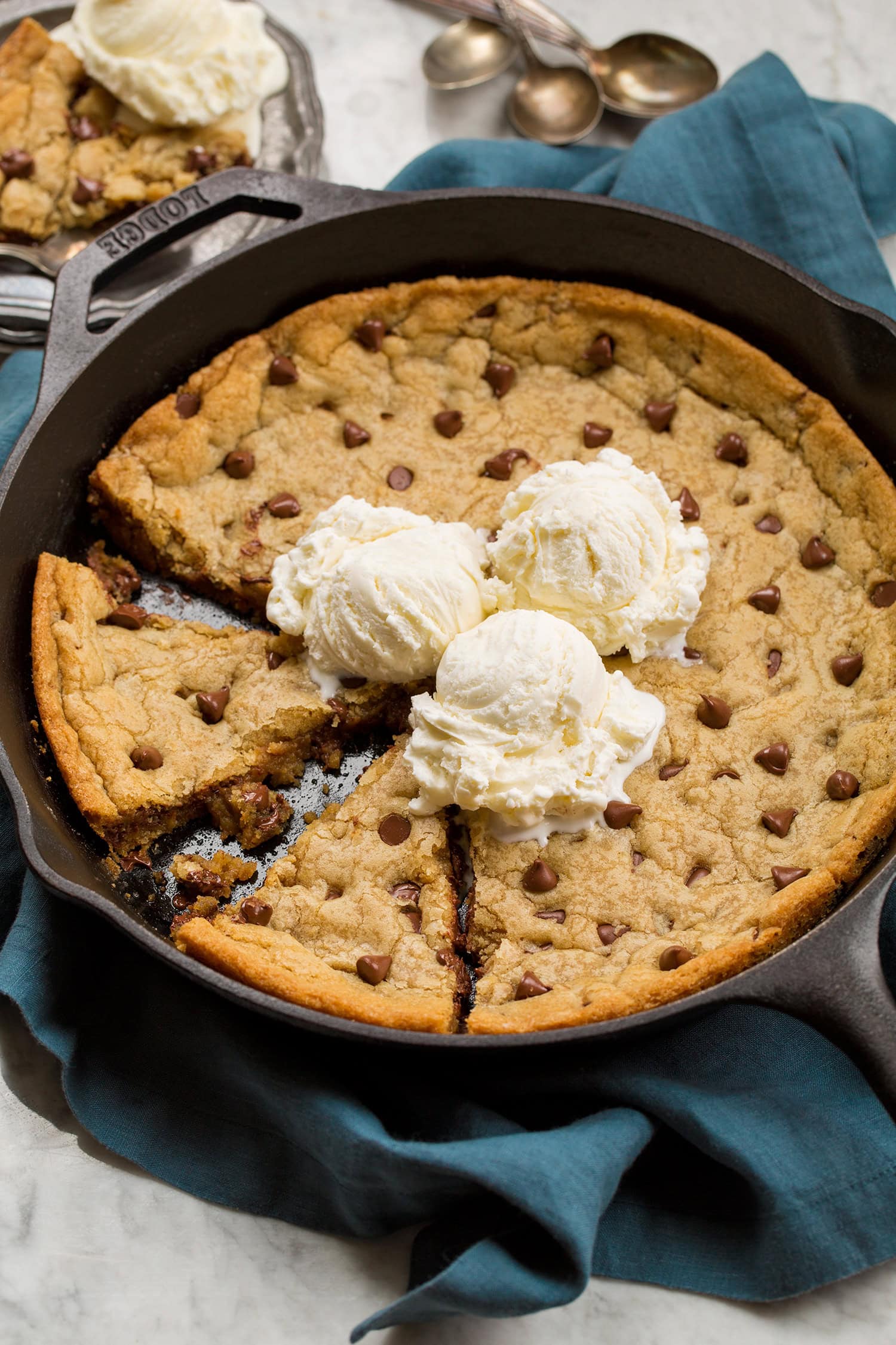 Skillet Chocolate Chip Cookie Skillet chocolate chip cookie with two wedges cut and three vanilla ice cream scoops on top.
