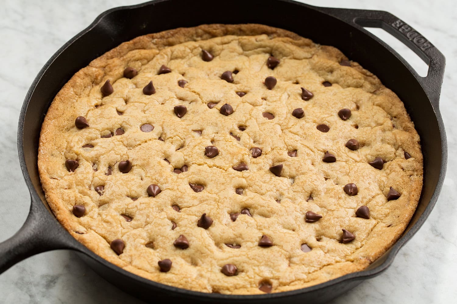 Skillet Chocolate Chip Cookie Whole skillet chocolate chip cookie shown in cast iron pan after baking and puffed.