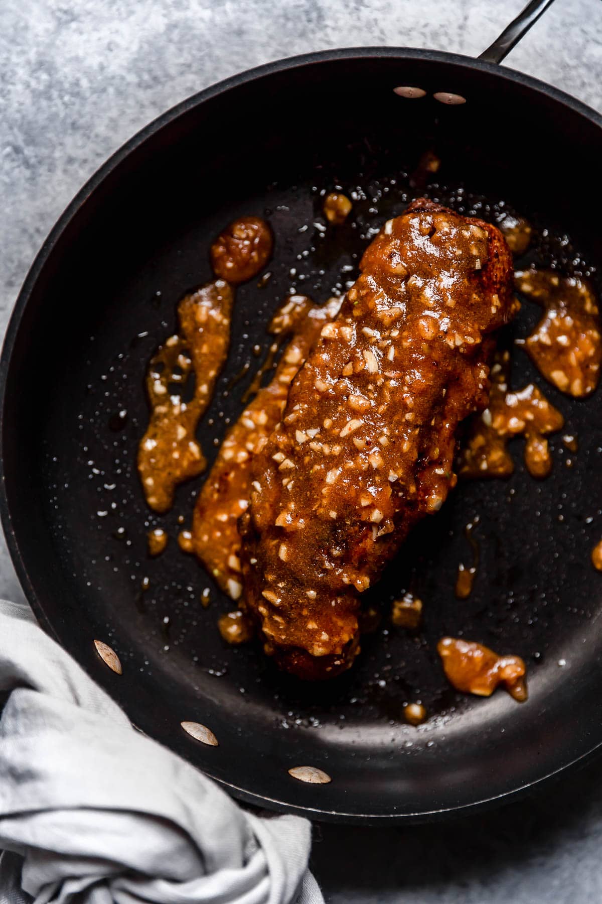 Island Pork Tenderloin Pork Tenderloin with rub and sauce searing in a large skillet.