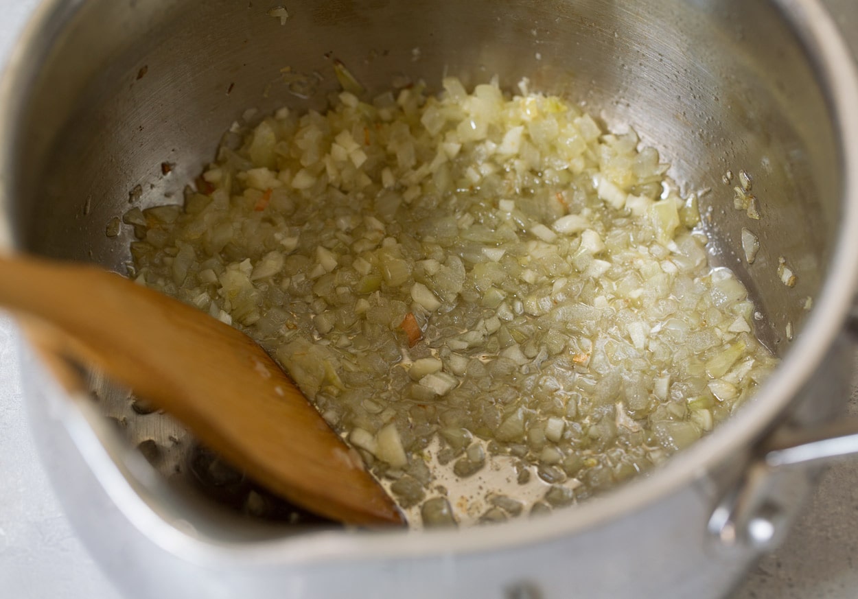 BEST Chicken Parmesan recipe! Sauteeing onions and garlic in saucepan for chicken parmesan marinara.