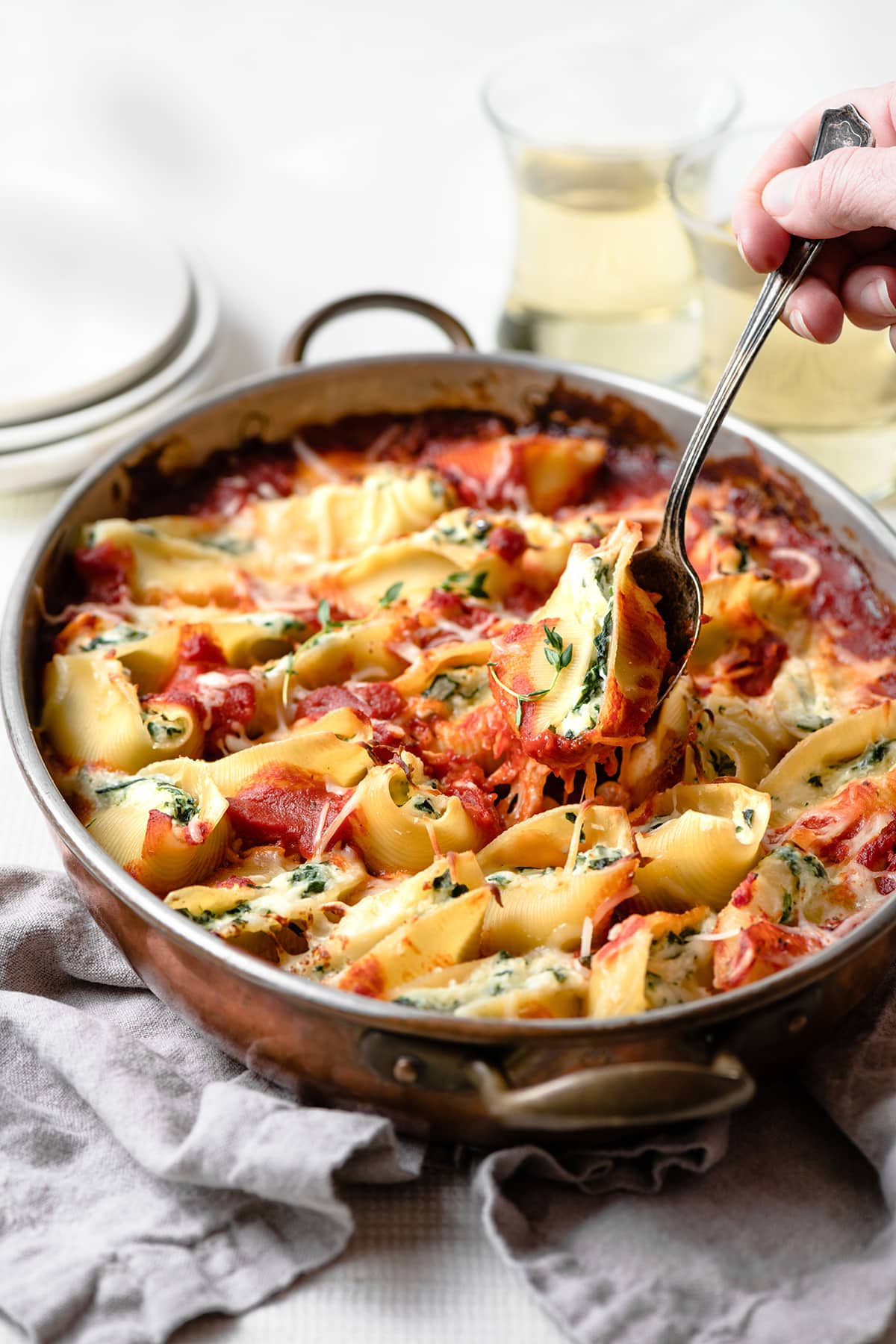 Spinach and Cheese Stuffed Shells Scooping one spinach and cheese stuffed shell from the casserole dish.