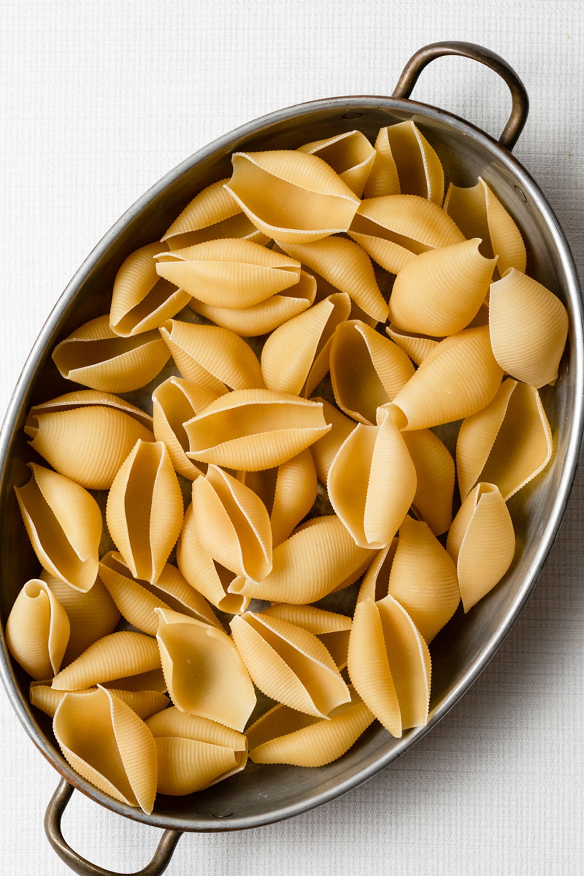 Spinach and Cheese Stuffed Shells Image of large pasta shells in a oval pewter baking dish.