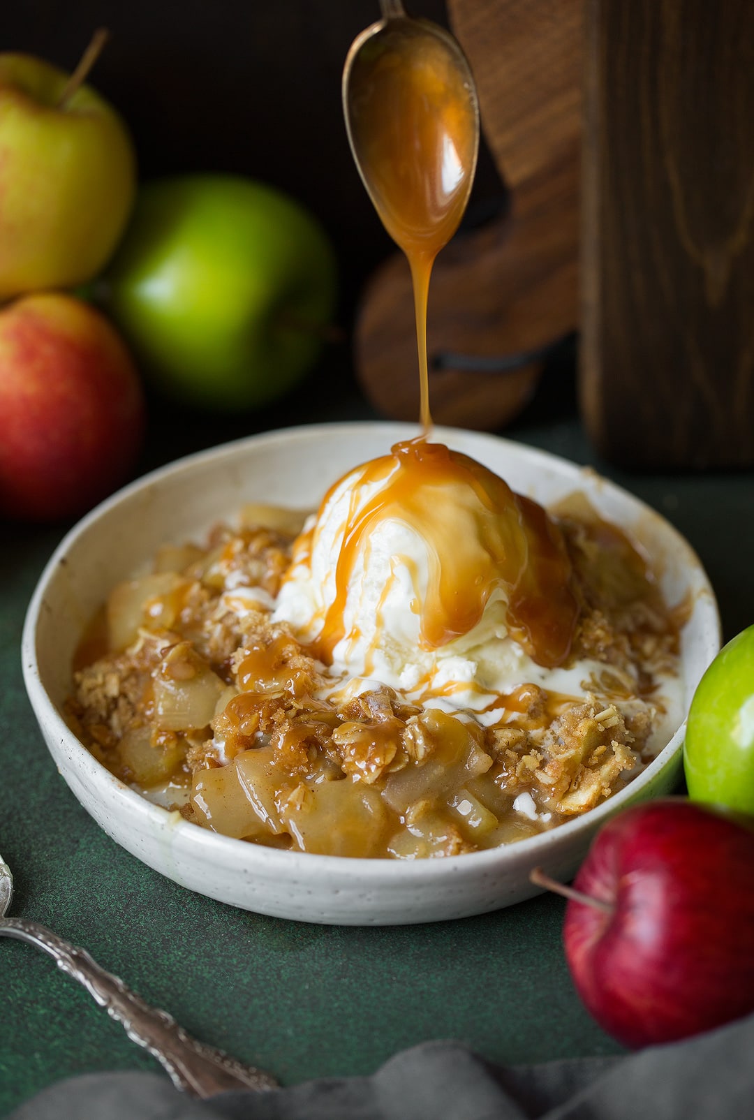 Apple Crisp Recipe Drizzling caramel sauce onto a bowl of apple crisp and scoop of ice cream
