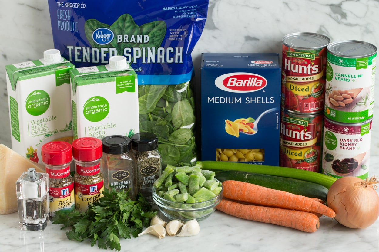 Minestrone Soup Minestrone Ingredients shown here including carrots, onion, celery, zucchini, beans, garlic, parsley, basil, oregano, parmesan, vegetable broth, spinach, pasta shells, canned tomatoes, and kidney beans.