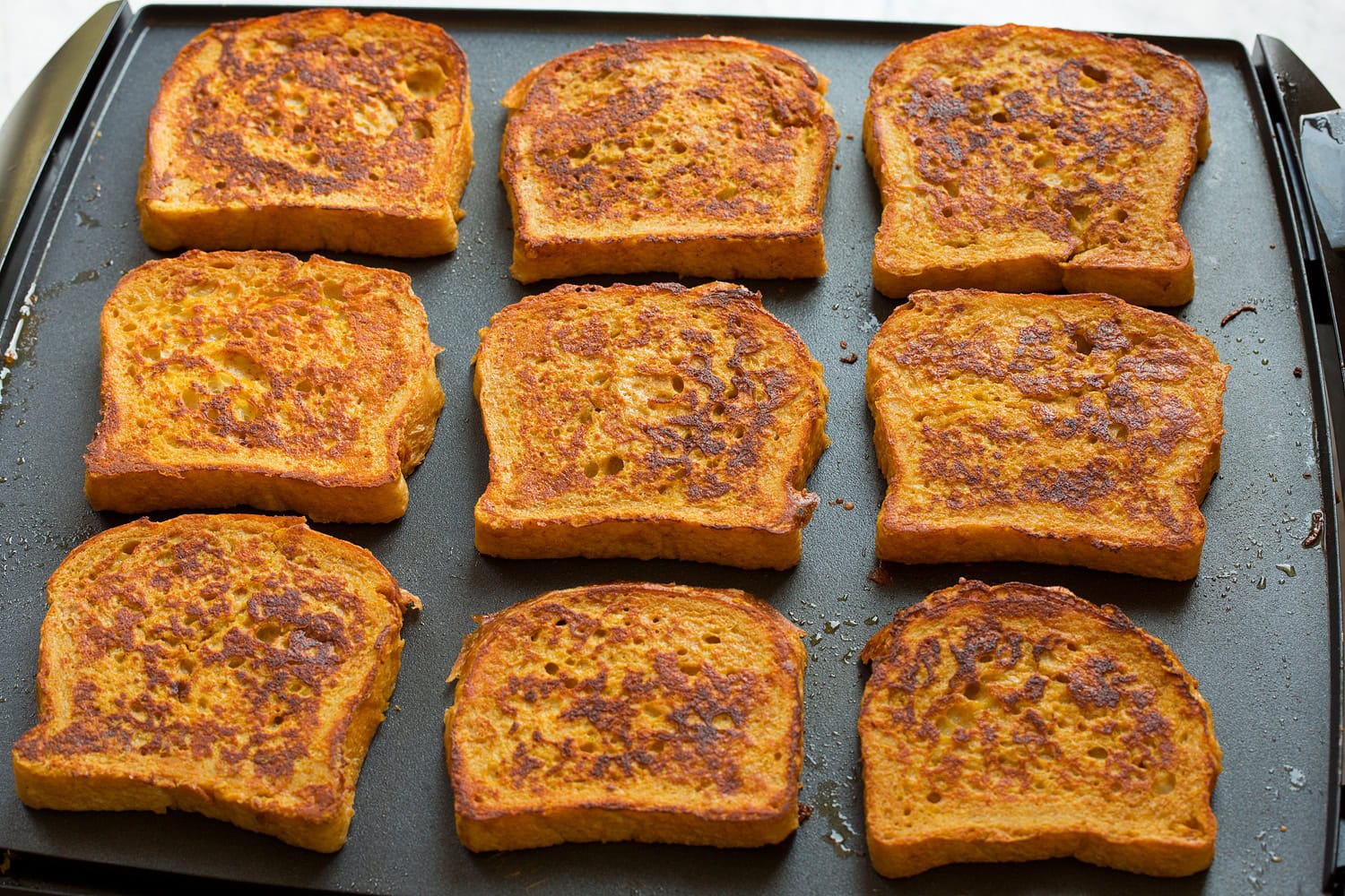 Pumpkin French Toast Pumpkin french toast cooking on a large non-stick griddle.