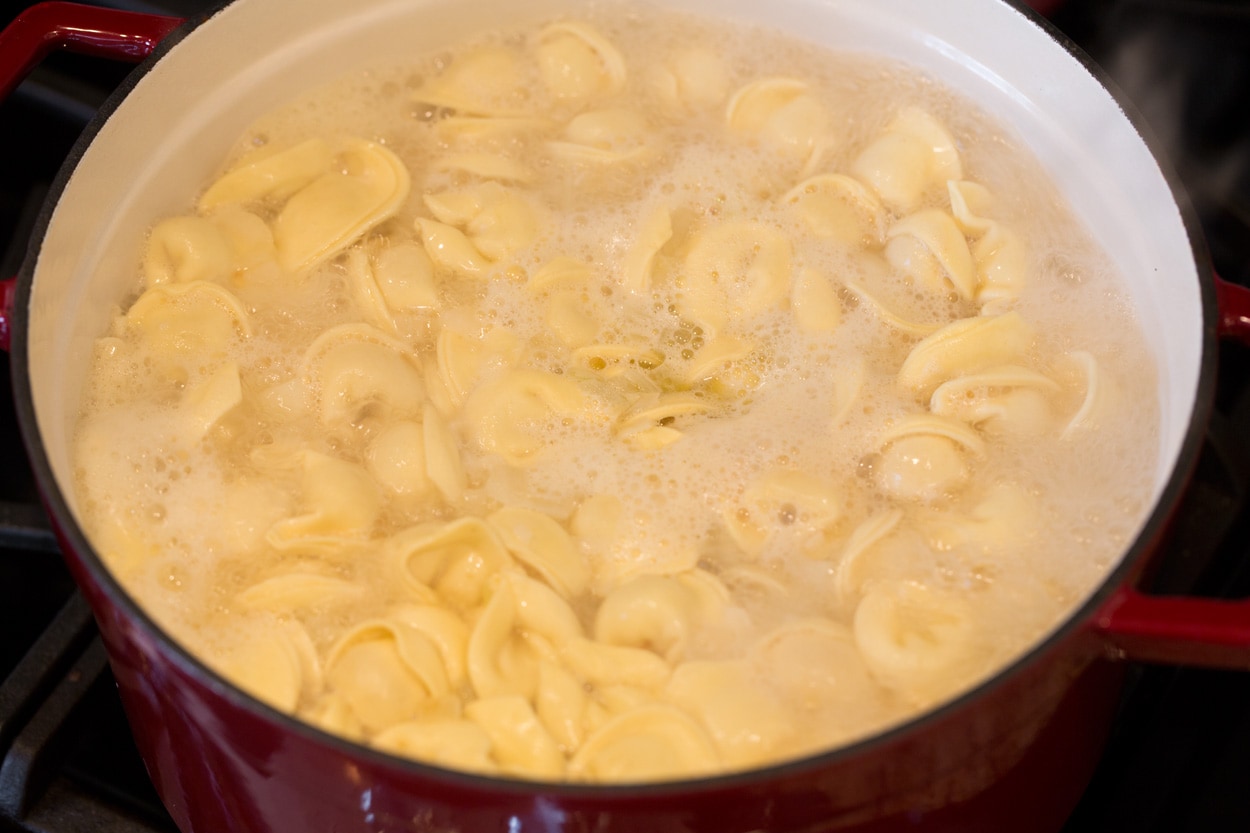 Tortellini Soup with Fresh Spinach Tomato and Garlic Boiling tortellini in broth mixture to make tortellini soup.