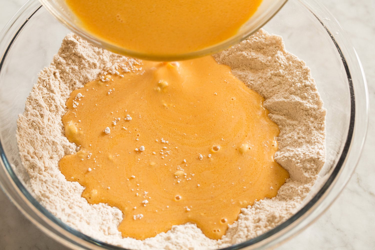 Pumpkin Waffles Wet pumpkin mixture added to dry flour mixture in a mixing bowl.