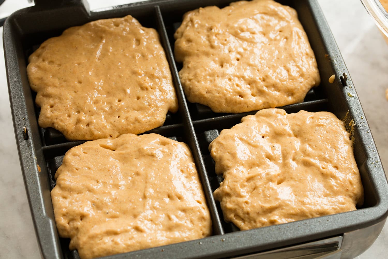 Pumpkin Waffles Pumpkin waffle batter shown in waffle iron before cooking.