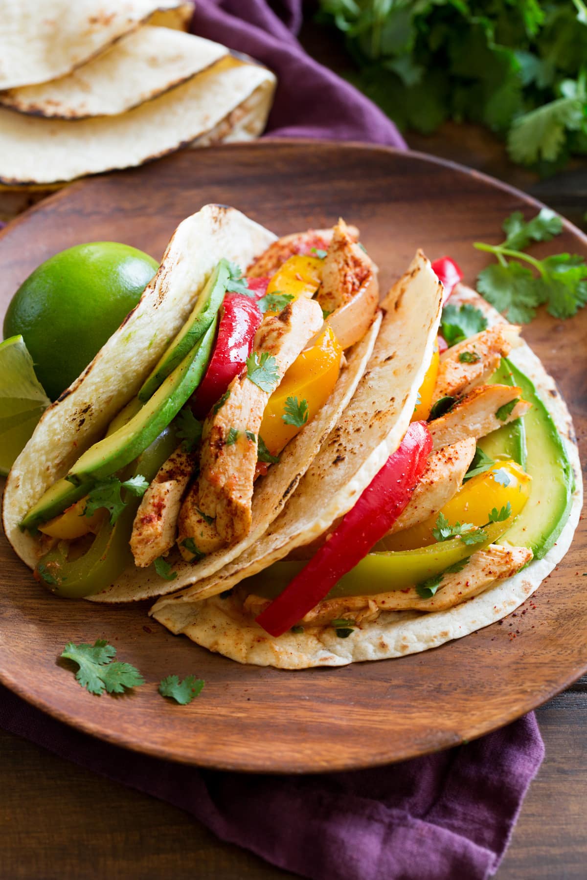 Easy Slow Cooker Chicken Fajitas Two chicken fajitas on a wooden plate.