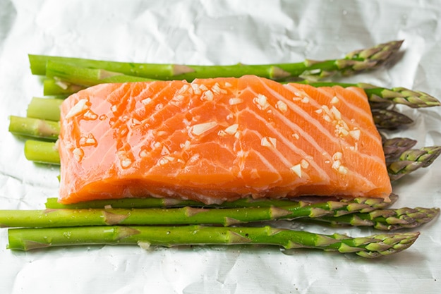 Baked Salmon in Foil Laying salmon over asparagus on sheet of foil.