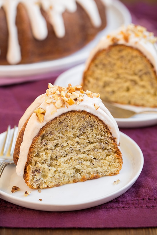 two slices of banana bundt cake with cream cheese icing on white plates