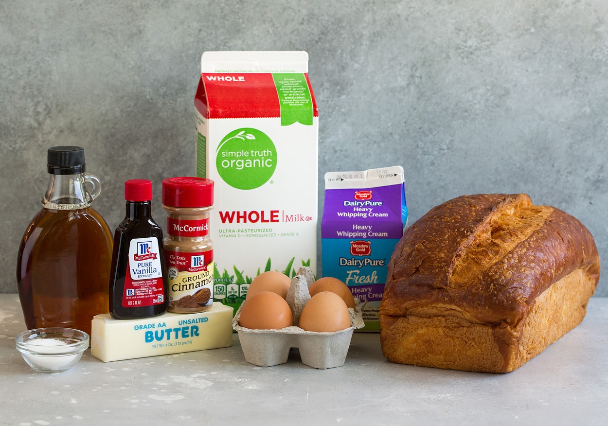 French Toast Ingredients needed to make french toast shown here including fresh bread, eggs, milk, cream, vanilla, cinnamon, butter, sugar and maple syrup.