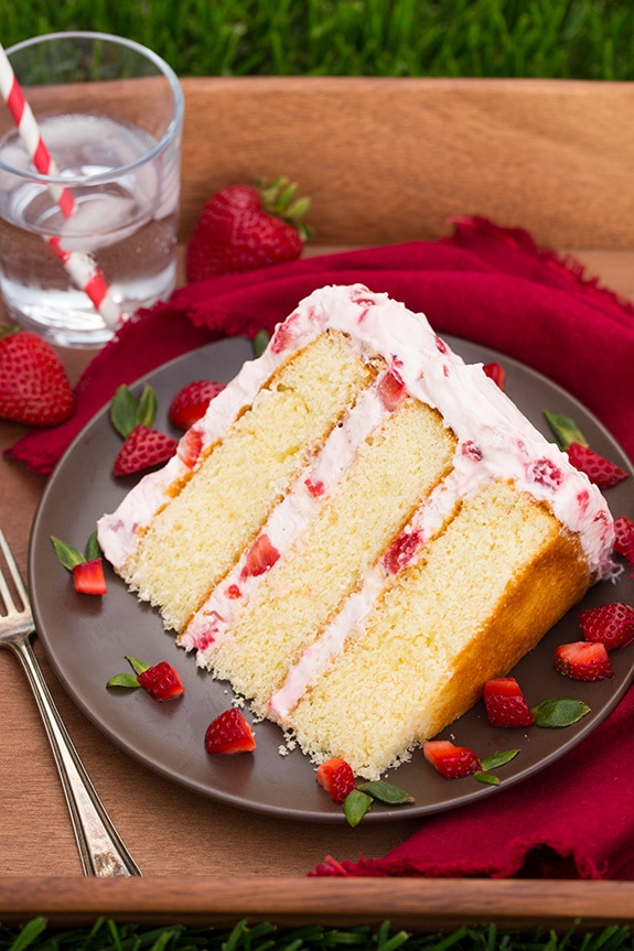 Fresh Strawberry Cake slice on a plate with cut up strawberries