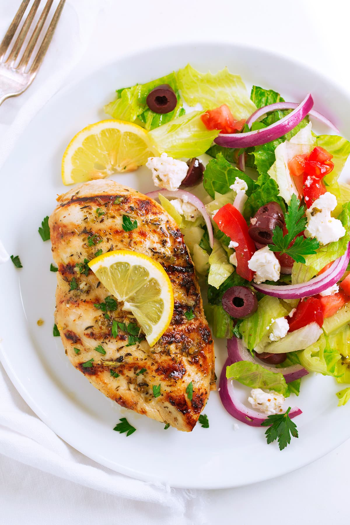 Greek Lemon Chicken Greek lemon chicken with a side salad on a serving plate.