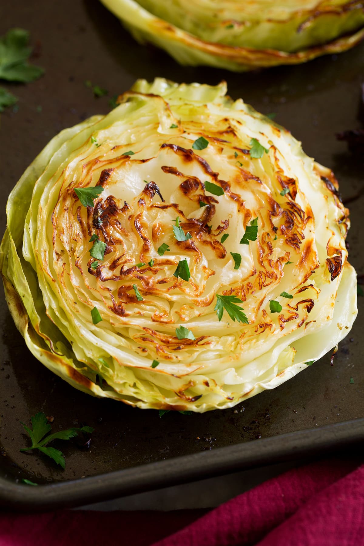 Roasted Cabbage Photo: A roasted cabbage slice is shown from close up. It is golden brown and garnished with parsley.