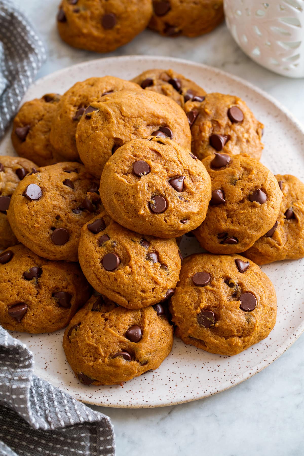 Pumpkin Chocolate Chip Cookies Image of pumpkin chocolate chip cookies stacked on a white serving plate.