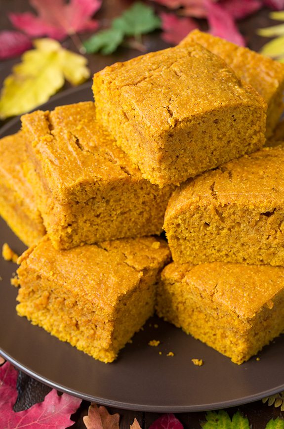 Pumpkin Cornbread Close up image of Pumpkin Cornbread slices staked on a dark brown plate.
