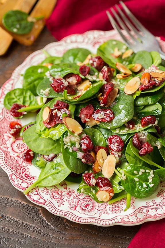 Cranberry Almonds Spinach Salad Spinach salad on a vintage red and white plate layered with dried cranberries, sliced almonds and a sesame seed dressing.