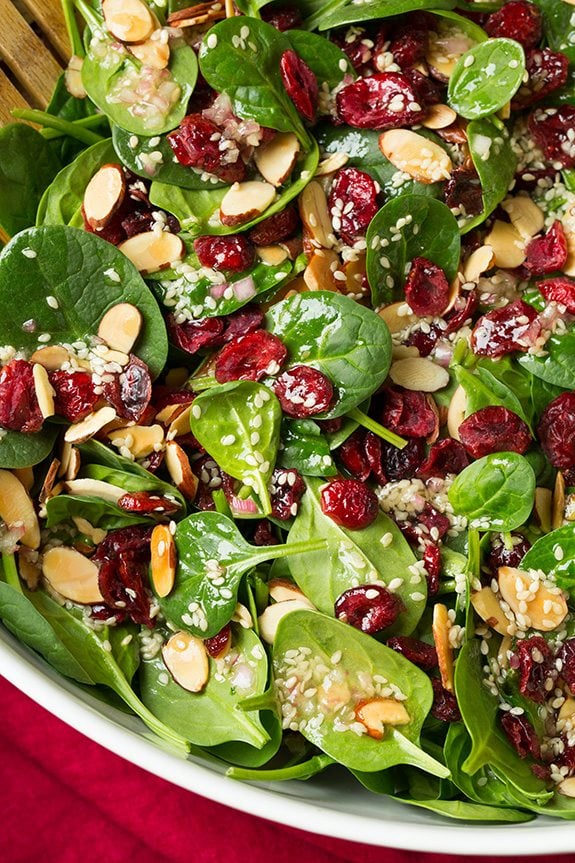 Cranberry Almond Spinach Salad Close up image of spinach salad in a white salad bowl.