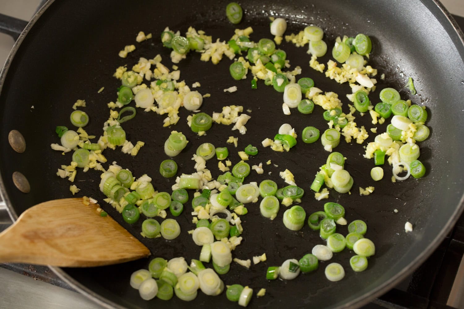 Thai Chicken Lettuce Wraps Green onions, garlic and ginger being sauteed in a skillet.