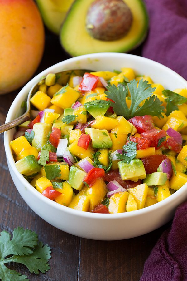 Shrimp Packs with Couscous and Mango Avocado Salsa Mango Avocado Salsa in a white serving bowl, set over a wooden table surface.