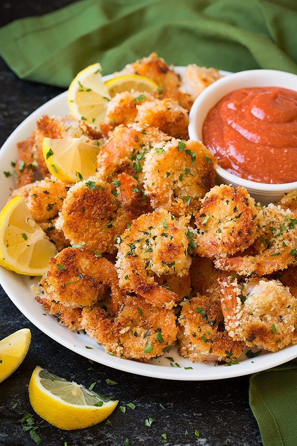 Crispy Panko Shrimp Shrimp with panko breading served on a white plate with a side of cocktail sauce and lemon wedges..