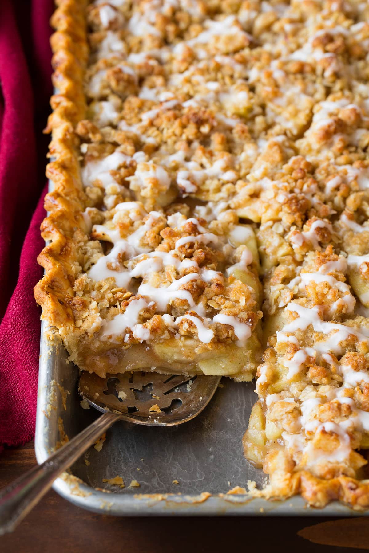 Scooping a slice of apple pie on a baking sheet.