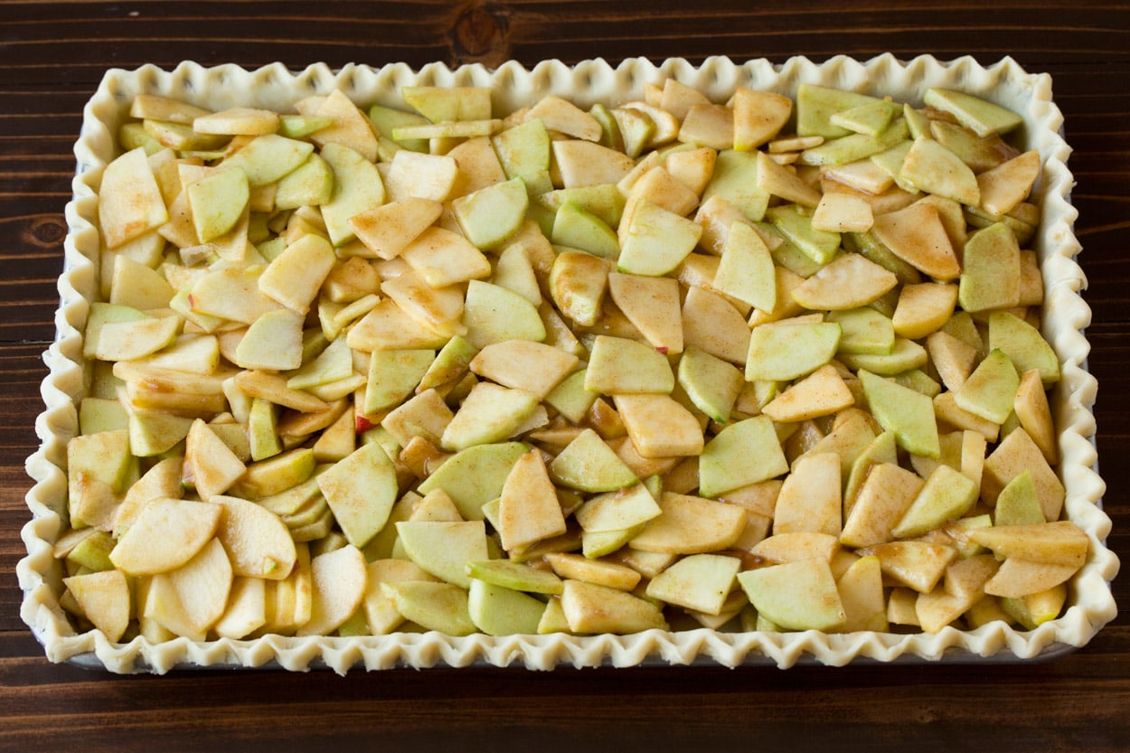 Apple filling added to crust layer for apple slab pie.