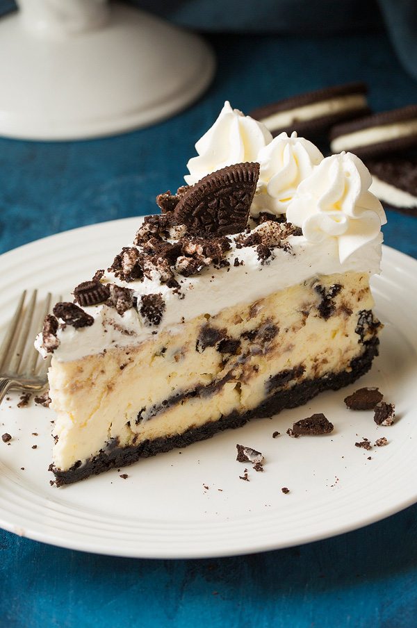 Oreo Cheesecake Oreo cheesecake on a white plate set over a blue surface. Cheesecake is made with Oreo crust, cream cheese and Oreo filling and topped with whipped cream.
