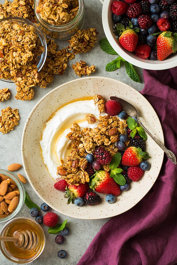 Homemade Honey Almond Granola Granola in a bowl with Greek yogurt, fresh fruit and honey.