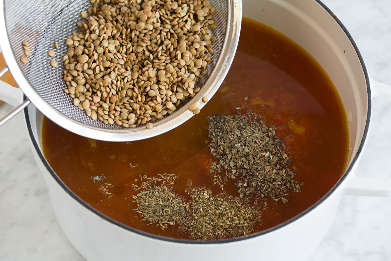 Lentil Soup adding lentils and herbs into a pot of soup