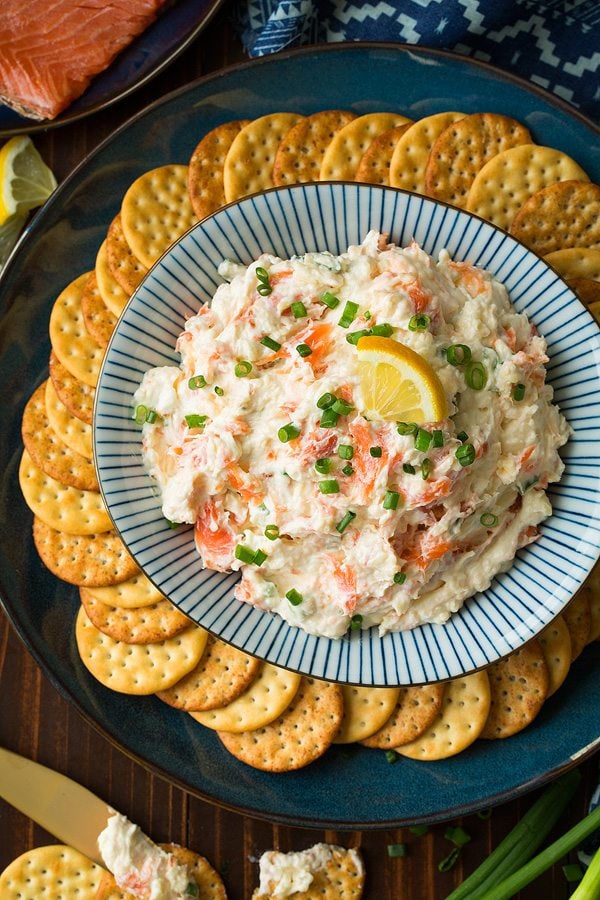 Smoked Salmon Dip Smoked Salmon Dip in a blue and white striped bowl set over a dark blue plate. Bowl is surrounded by a circle of crackers.