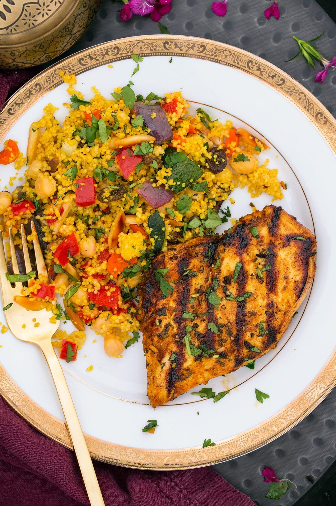 Couscous with Roasted Vegetables, Chick Peas and Almonds Couscous served on a a white plate with chicken.