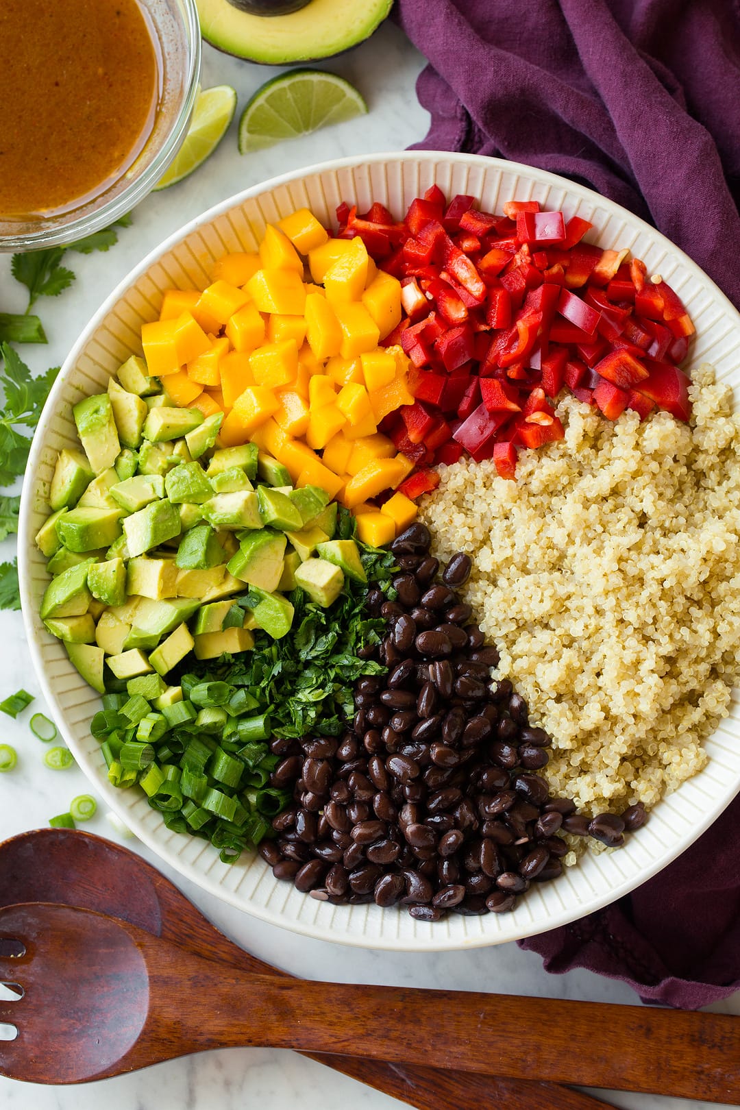 Quinoa Salad with Black Beans Mangoes and Avocados Quinoa black bean salad ingredients shown in individual portions before tossing in a white salad bowl.