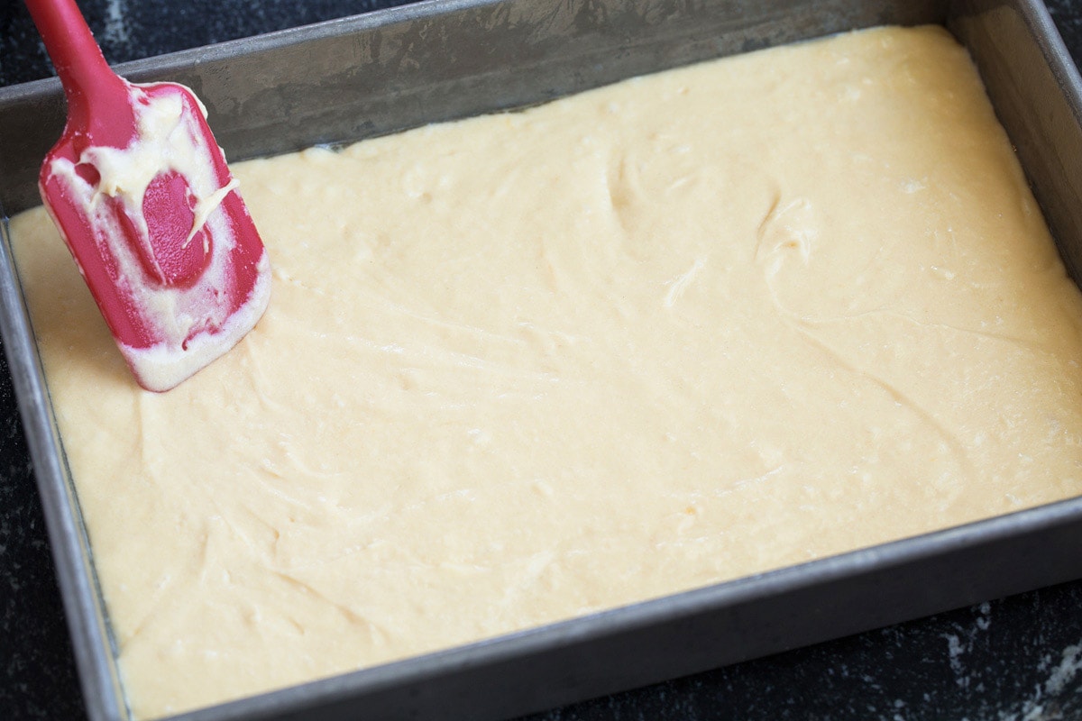 Tres Leches Cake - one of the BEST Mexican desserts! A sponge-type cake is soaked in a blend of rich milks, covered with whipped cream and dusted with cinnamon or served with strawberries. So good! #tresleches #cake #Mexicanrecipe #dessert Spreading tres leches cake batter in cake pan.