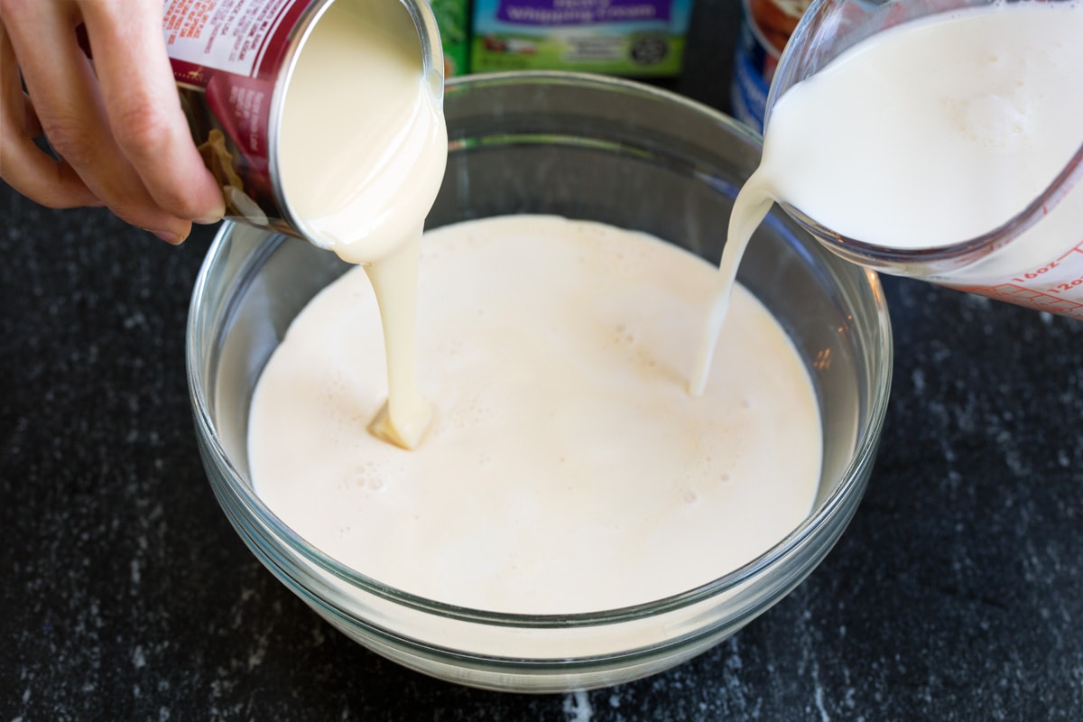 Tres Leches Cake - one of the BEST Mexican desserts! A sponge-type cake is soaked in a blend of rich milks, covered with whipped cream and dusted with cinnamon or served with strawberries. So good! #tresleches #cake #Mexicanrecipe #dessert Mixing three milks in a glass mixing bowl.