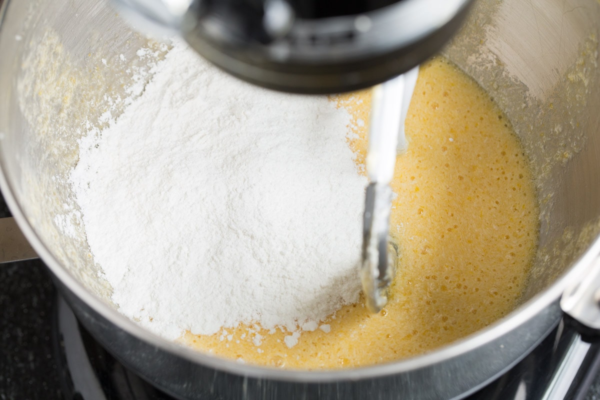 Tres Leches Cake - one of the BEST Mexican desserts! A sponge-type cake is soaked in a blend of rich milks, covered with whipped cream and dusted with cinnamon or served with strawberries. So good! #tresleches #cake #Mexicanrecipe #dessert Mixing flour mixture into sugar and egg mixture in mixer bowl.