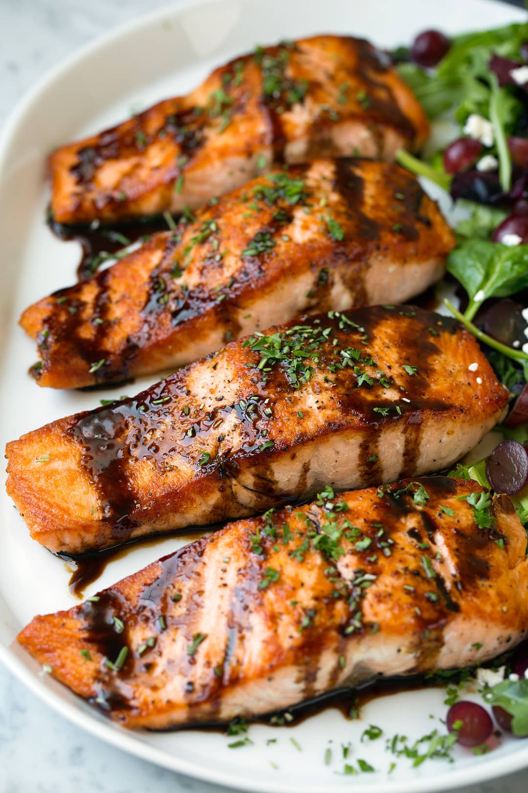 Balsamic Glazed Salmon fillets on white platter with salad