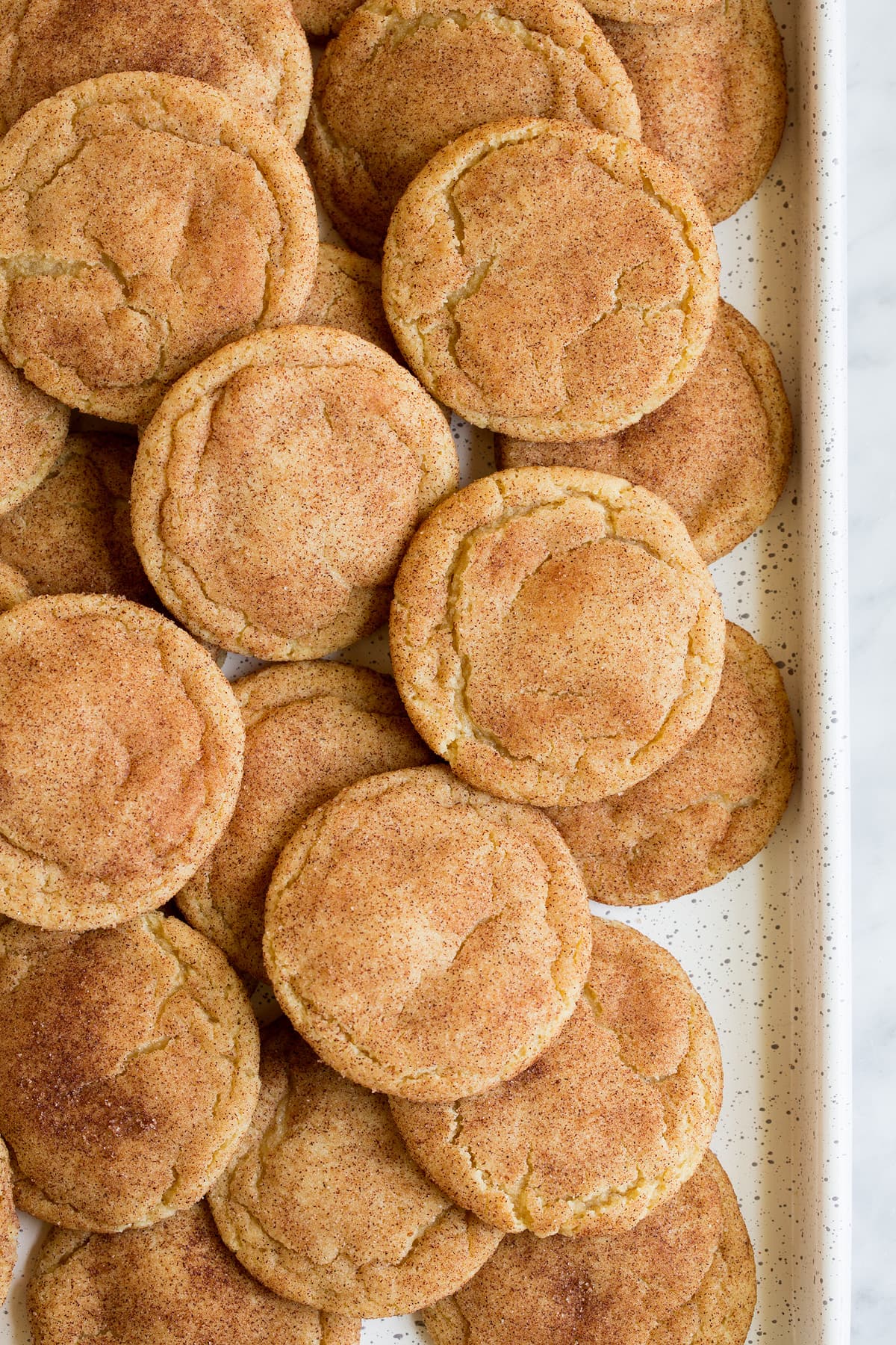 Snickerdoodle Cookies Overhead image of a white cookie sheet layered with snickerdoodle cookies.