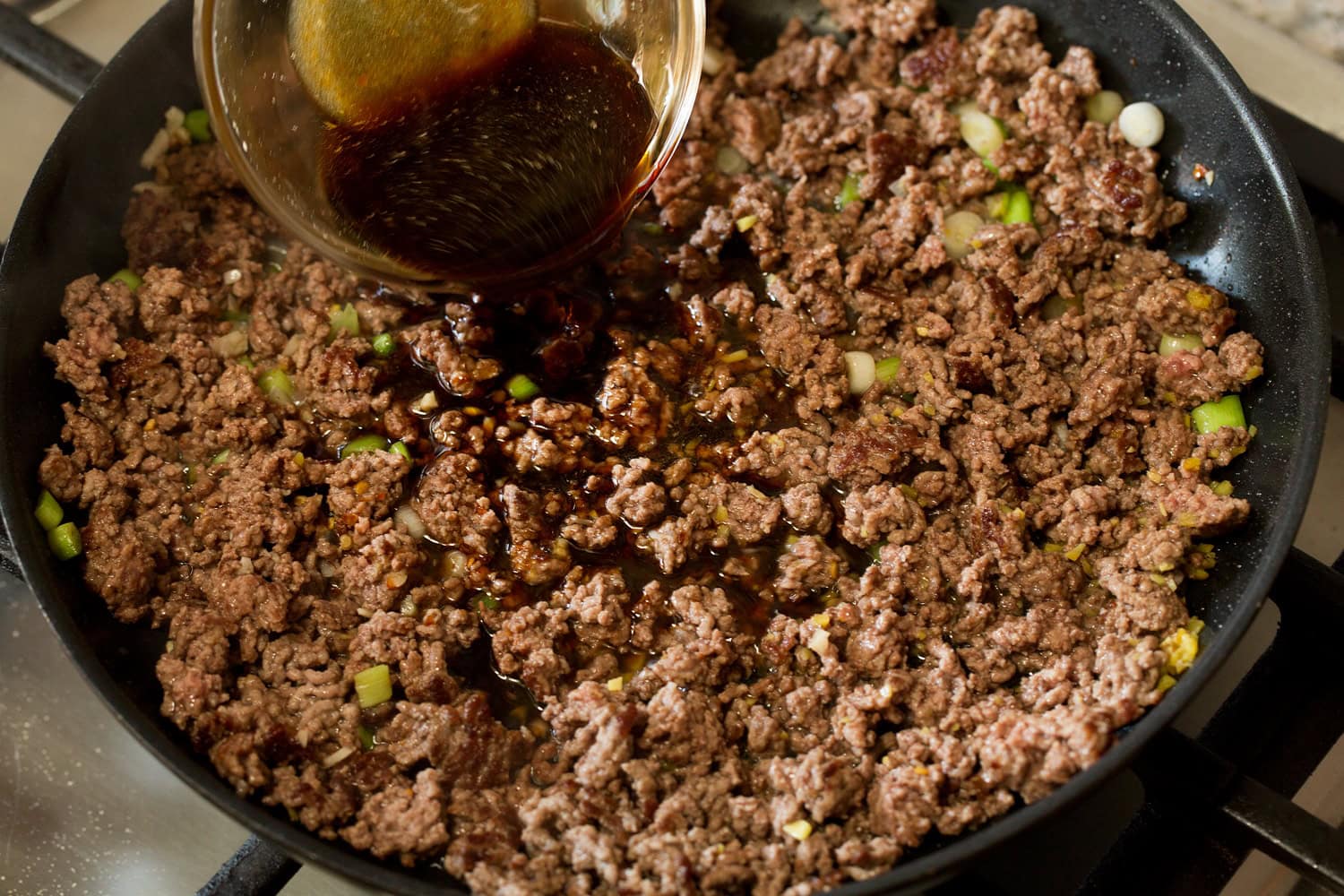 Korean Beef Bowls Crumbled browned beef with soy sauce mixture being added.