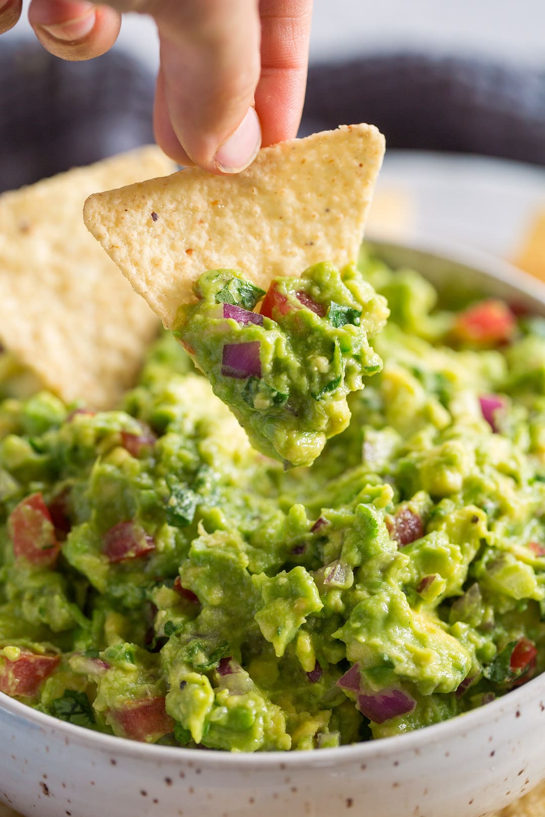 Homemade Guacamole dipping a tortilla chip into fresh guacamole dip