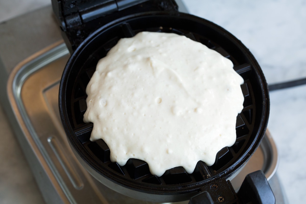 Belgian Waffles Pouring waffle batter onto Belgian waffle iron.