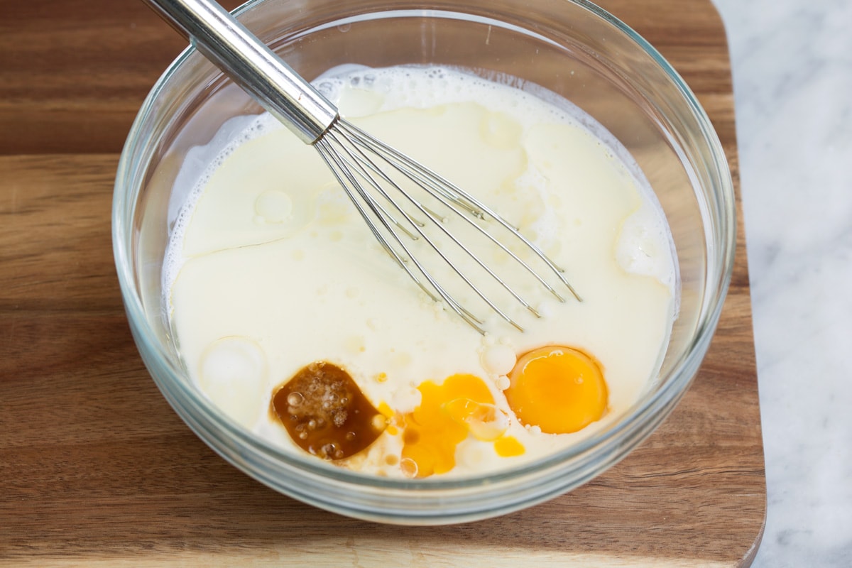 How to Make Perfect Belgian Waffles - with step by step instructions! These are easily the best waffles you'll try! Light and fluffy and tender inside and deliciously crisp outside. #belgian #waffles #breakfast Whisking wet ingredients for belgian waffle batter in a glass mixing bowl.