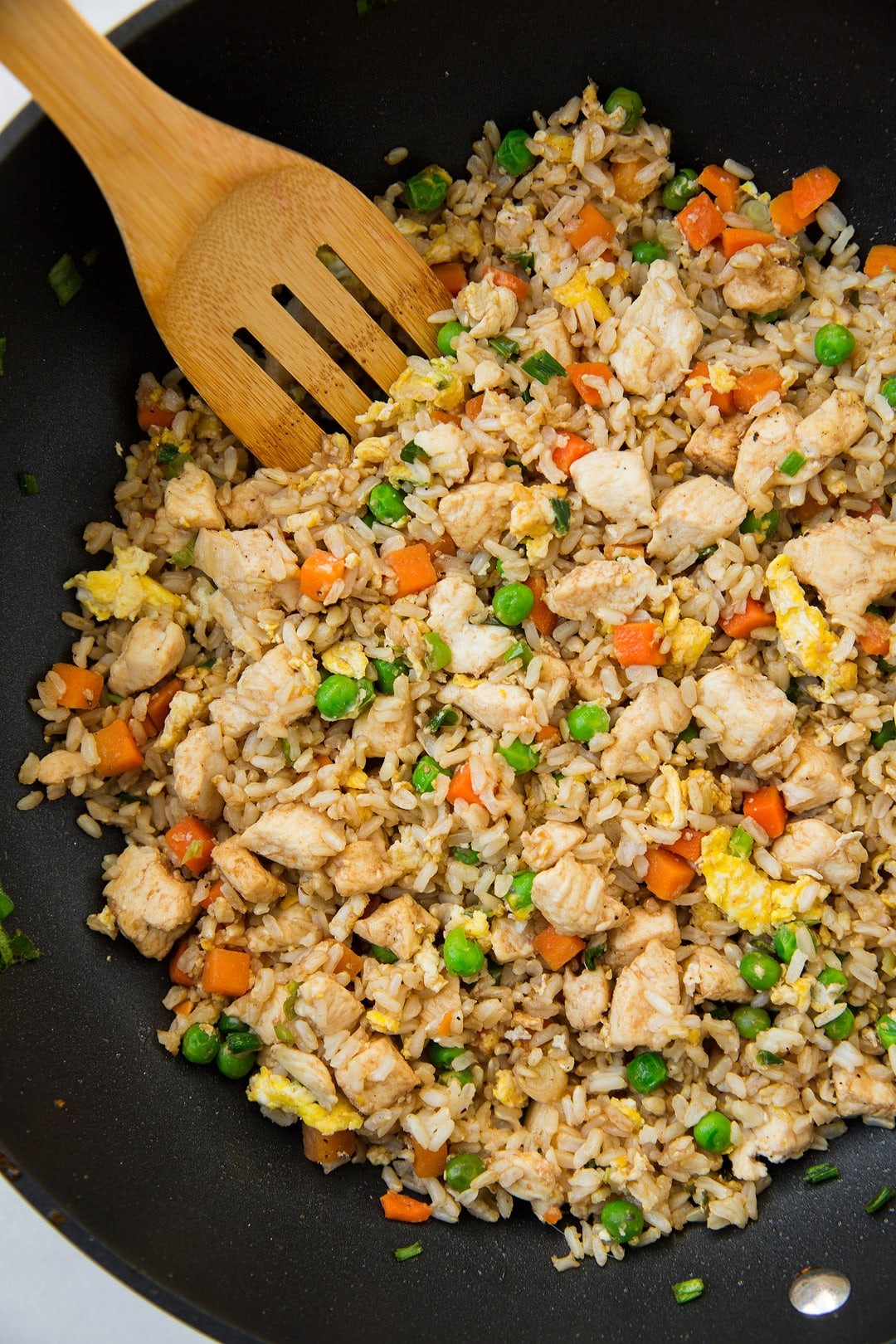 An easy flavorful fried rice that's made with brown rice and lean chicken breast instead of white rice and ham. A recipe everyone can agree on! Hearty and so satisfying. It make great leftovers too. | Chicken Fried Rice | Chinese Take Out | #cookingclassy #rice #chicken Chicken fried rice in a wok with a wooden spatula.