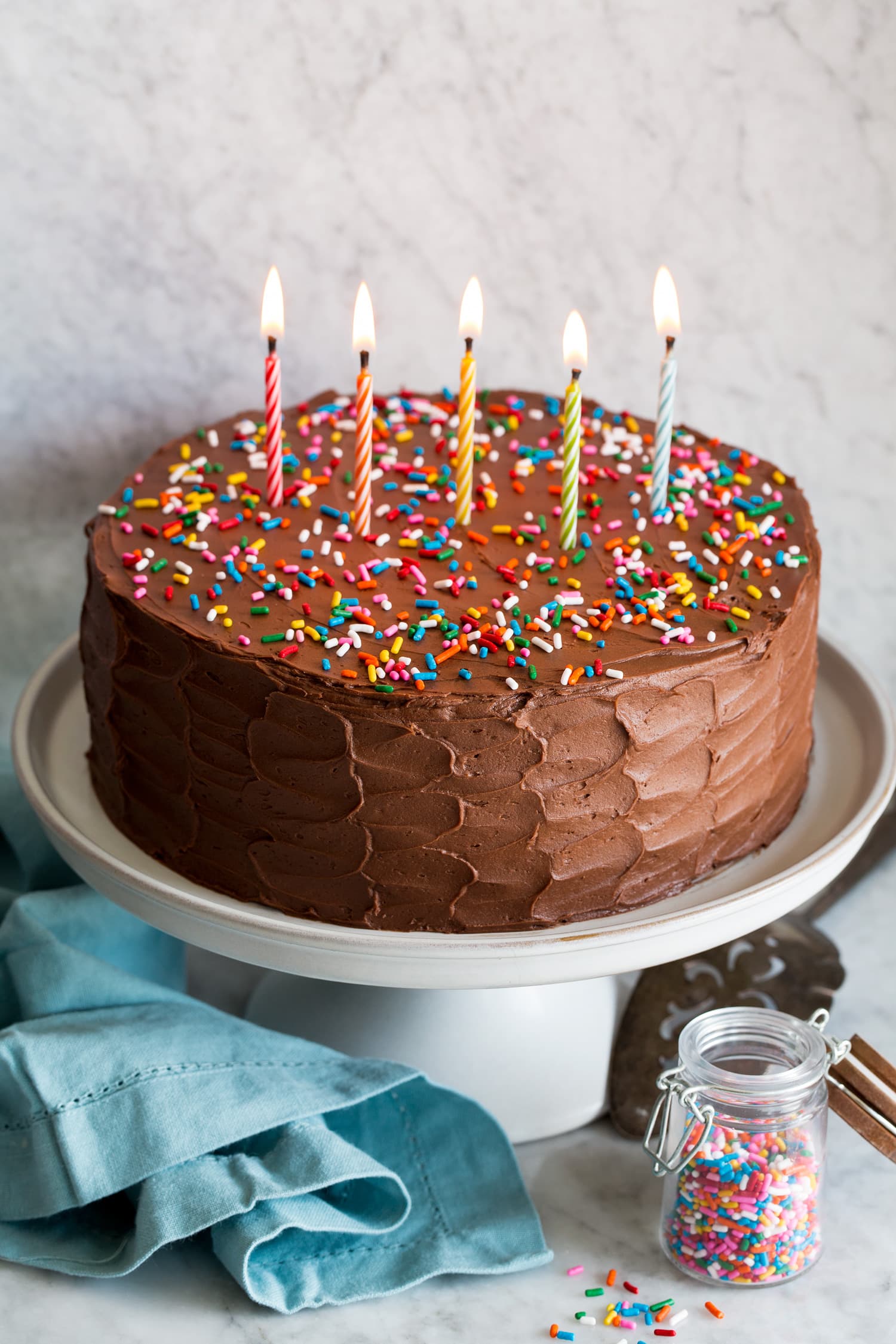 Yellow Cake Whole cake with chocolate buttercream frosting and lit candles.