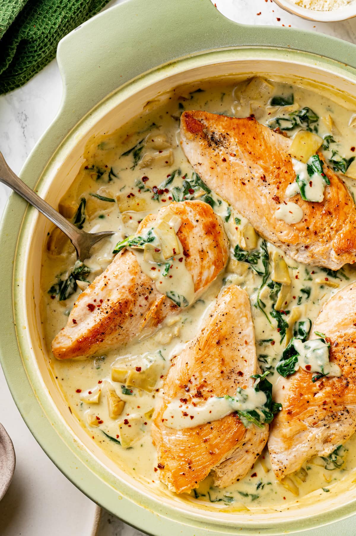 Spinach Artichoke Chicken Overhead view of creamy spinach artichoke chicken in a large skillet.