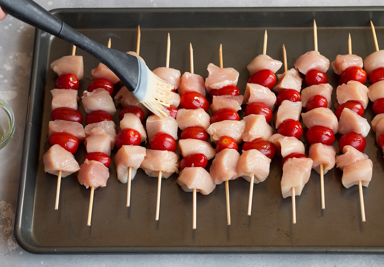 brushing olive oil onto chicken skewers