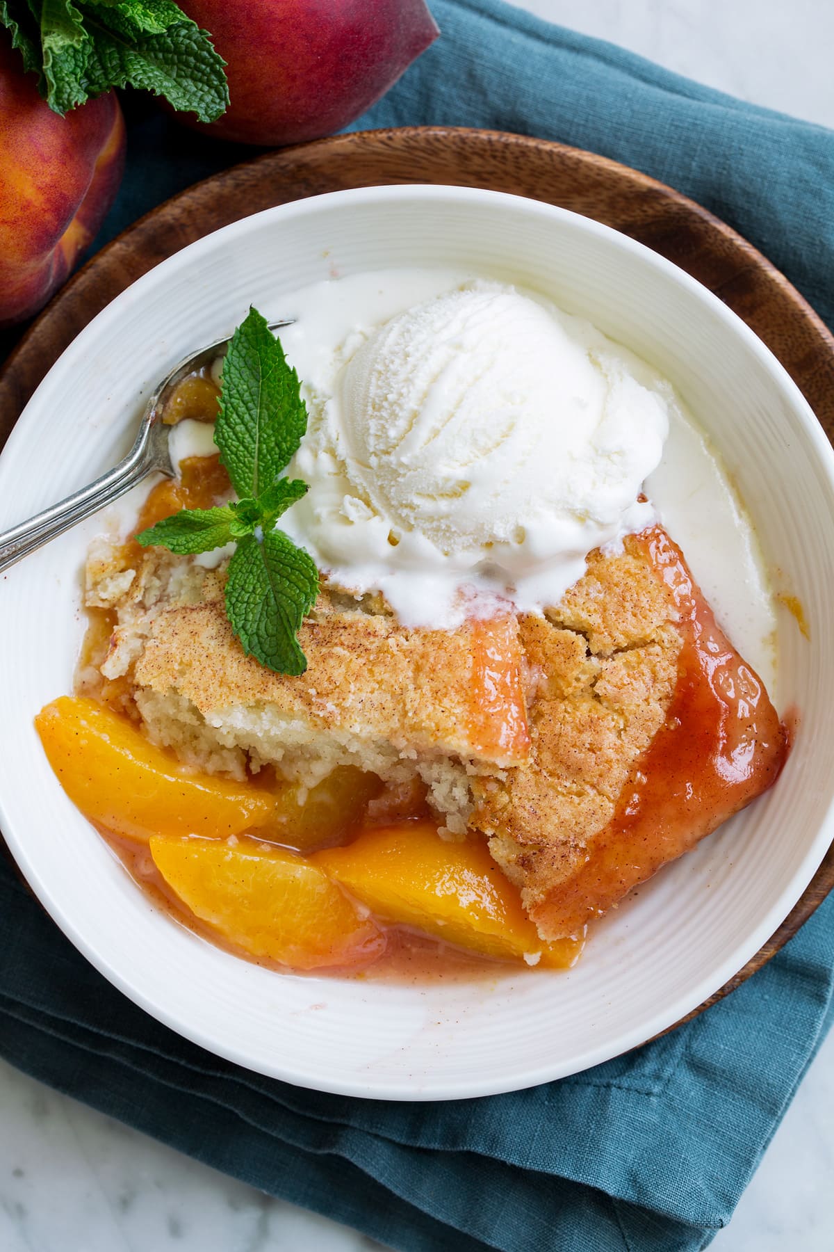 Peach Cobbler - the only peach cobbler recipe you'll ever need! I've never found better! Light and fluffy, buttery topping and perfectly sweet and juicy peach filling. #peach #cobbler #dessert #recipe Overhead close up image of peach cobbler showing texture of filling and topping.