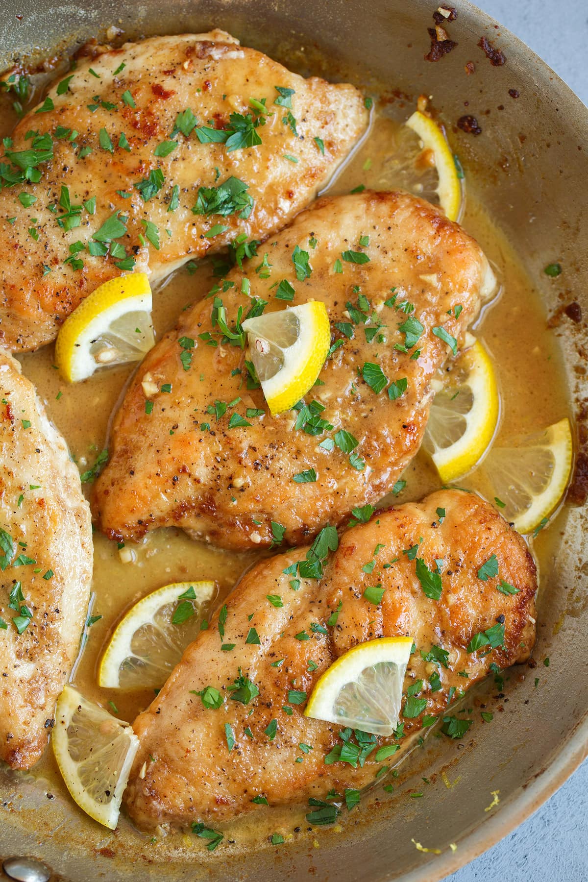 Lemon Butter Chicken Lemon Chicken in a skillet. Chicken cutlets are pan seared and golden brown and served in a rich butter sauce, garnished with parsley.